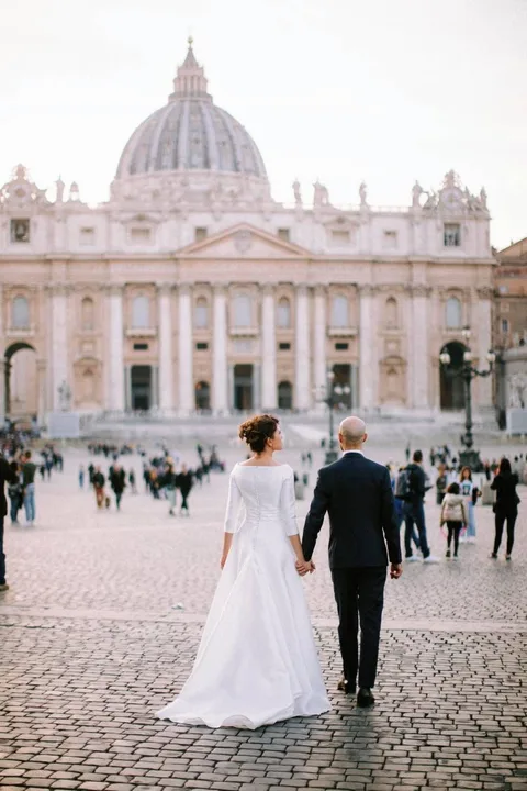 Una coppia di sposi passeggia mano nella mano in Piazza San Pietro, nel Vaticano · foto 15